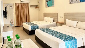 A hotel room with two beds, a desk with a tray of water bottles, a ceiling fan, and a painting of a coastal scene. - Lavigo Resort (Langkawi)