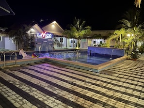 A nighttime swimming pool area with a neon sign, palm trees, and a tiled walkway. - Lavigo Resort (Langkawi)