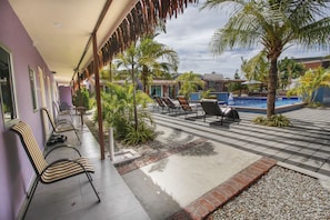 A poolside area with lounge chairs, a swimming pool, and palm trees.