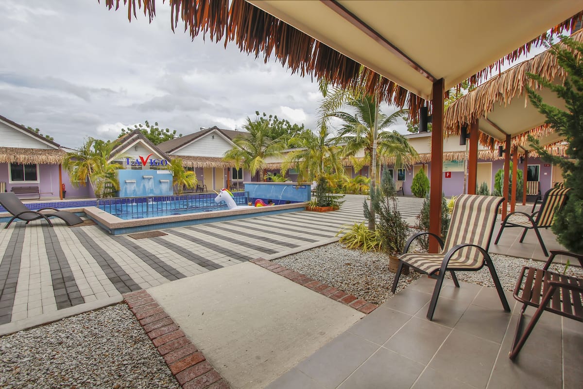 A resort with a pool, lounge chairs, and thatched-roof buildings.