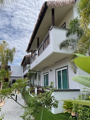 A multi-story building with balconies, surrounded by tropical plants and a clear sky. - Lavigo Resort (Langkawi)