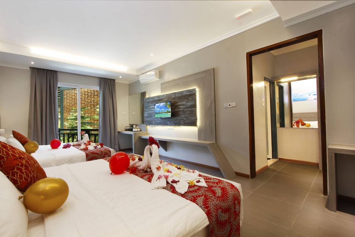 A hotel room with two beds, a TV, and a balcony with a view.