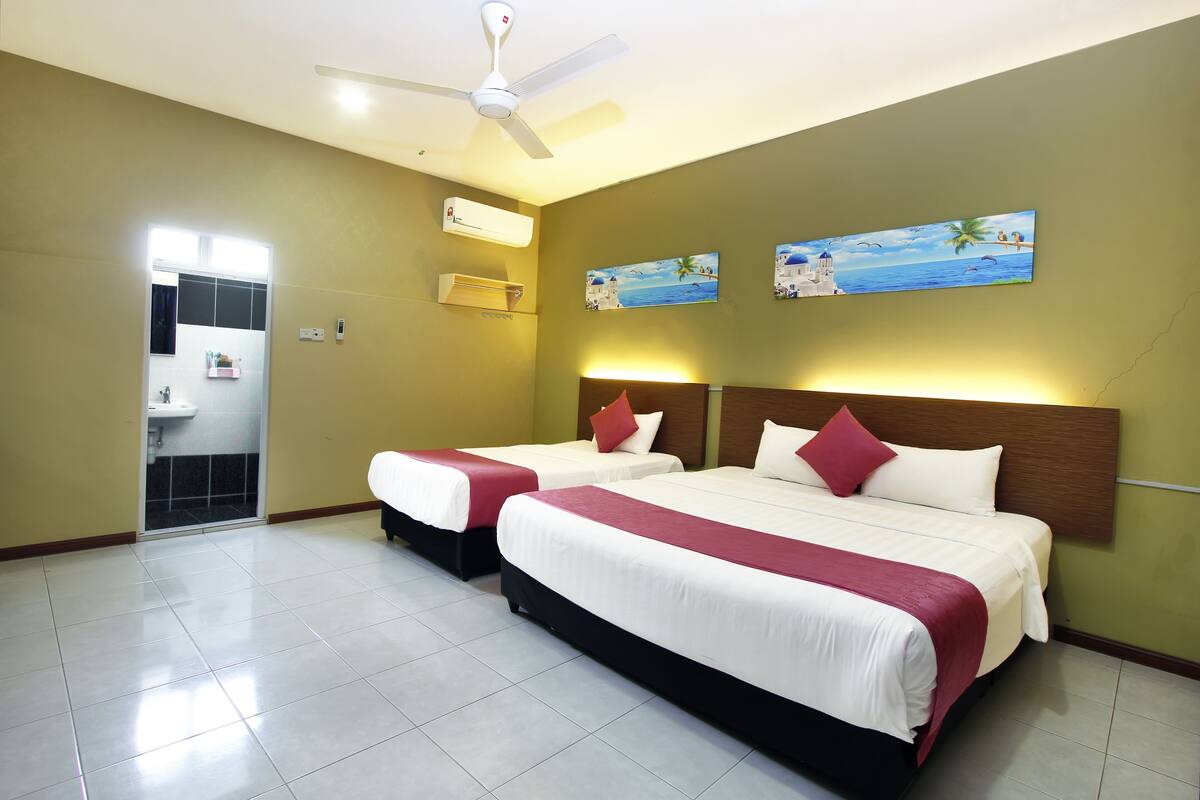 A hotel room with two beds, a ceiling fan, an air conditioning unit, and a bathroom visible through an open door.