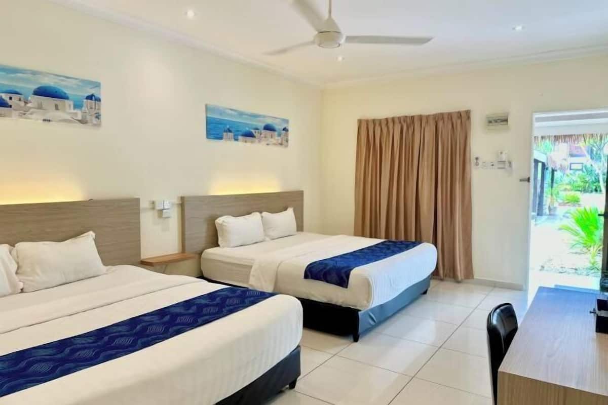 A hotel room with two beds, a desk, and a view of the outside.