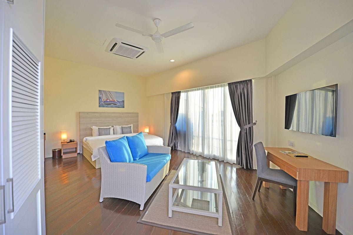 Une chambre d’hôtel équipée d’un lit, d’un bureau, d’une chaise, d’une télévision et d’un ventilateur de plafond.