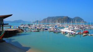 Ein Yachthafen mit zahlreichen vor Anker liegenden Booten, einem strahlend blauen Himmel und einer Berginsel im Hintergrund.