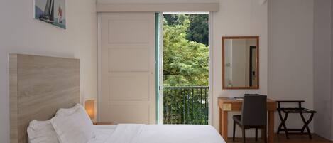 A bedroom with a bed, a desk, and a chair.