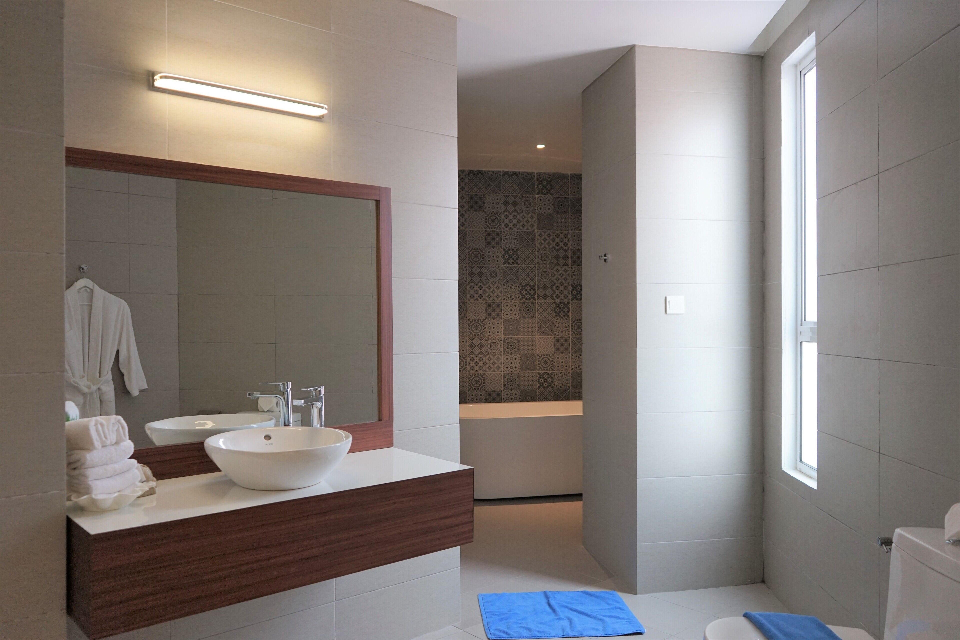 A modern bathroom with a large mirror, two sinks, and a shower area.