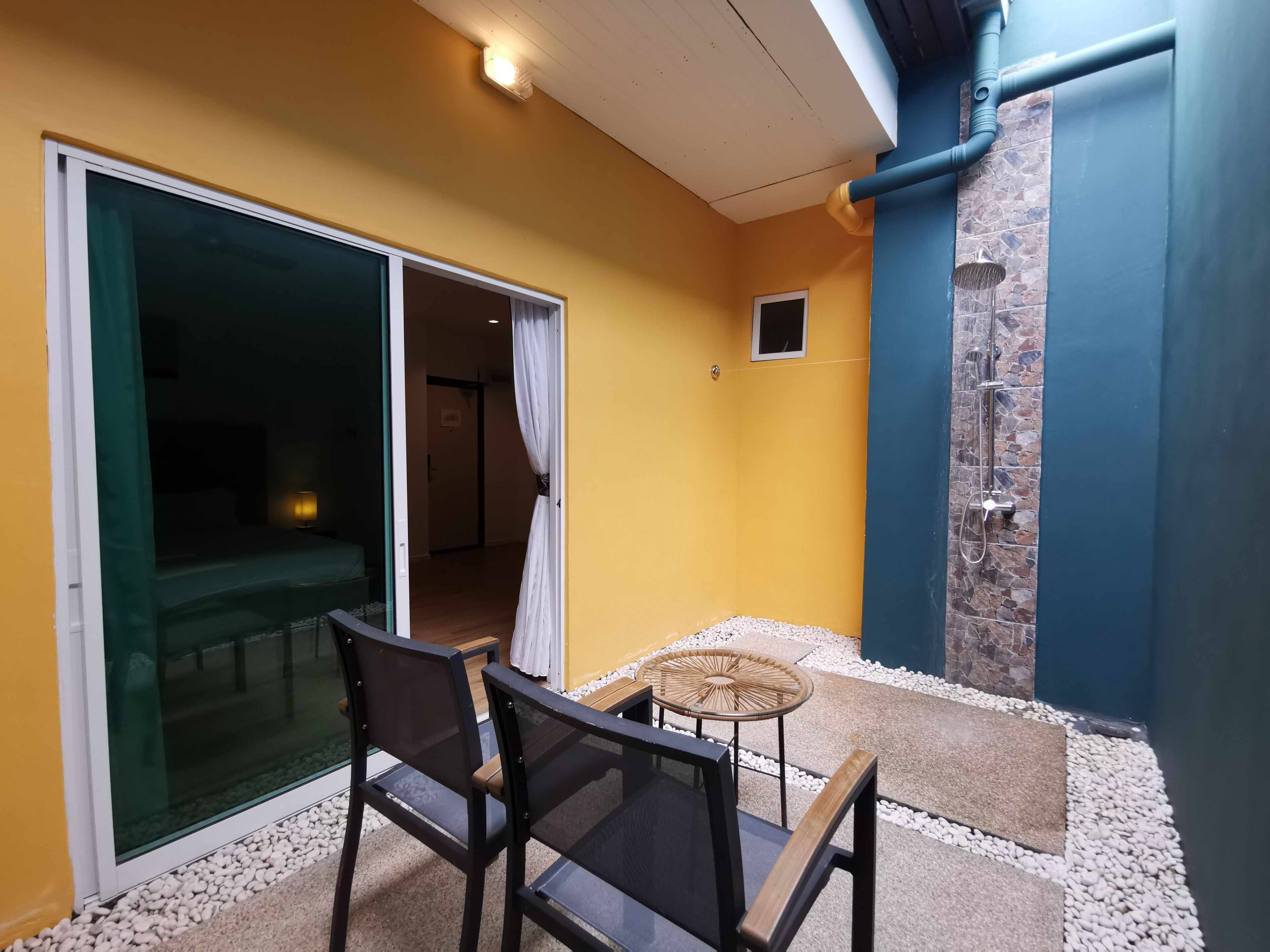 Un balcón con mesa y sillas, una puerta corrediza de vidrio y un ventanal pequeño.