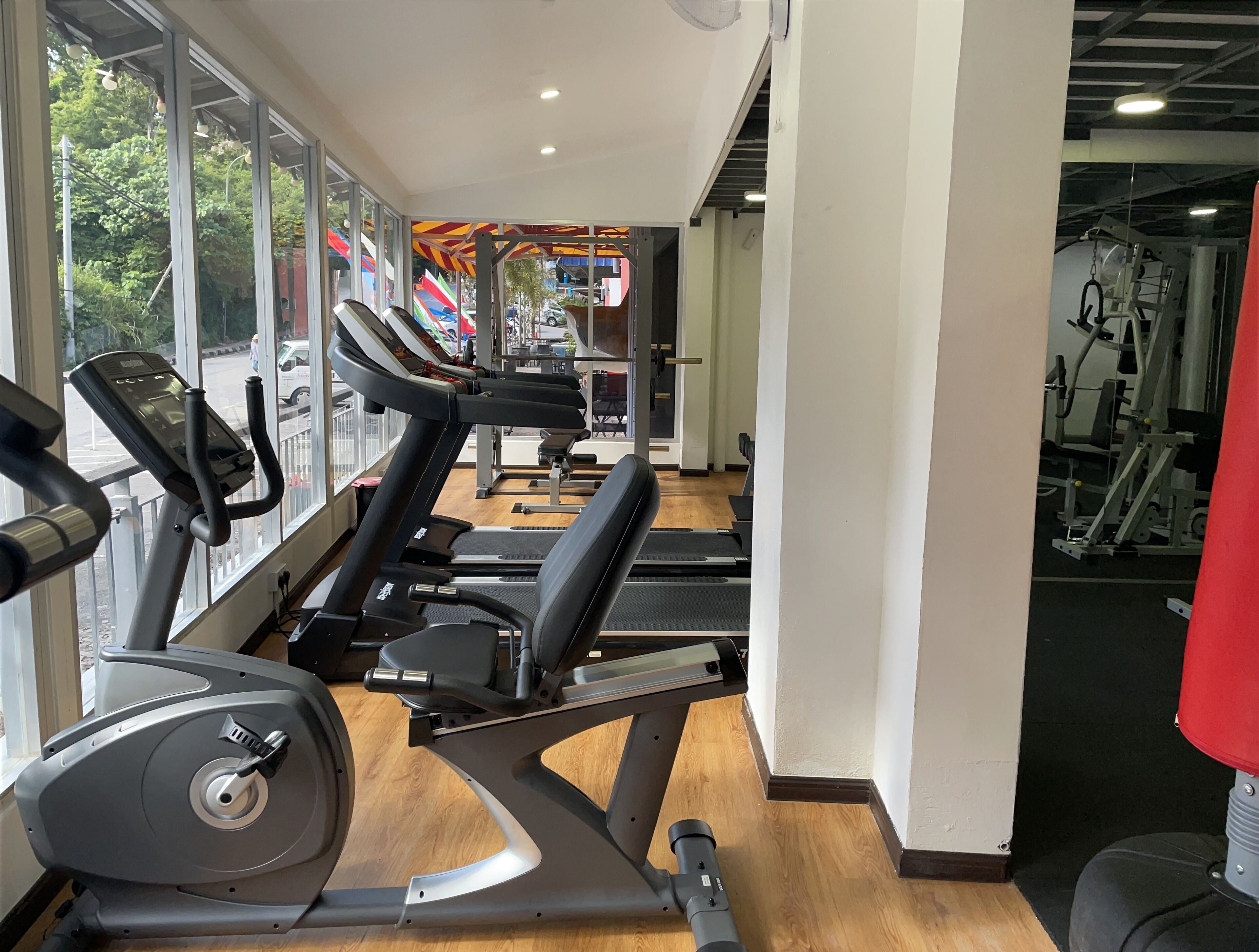 A gym with treadmills and exercise equipment, large windows, and a view of the outside.