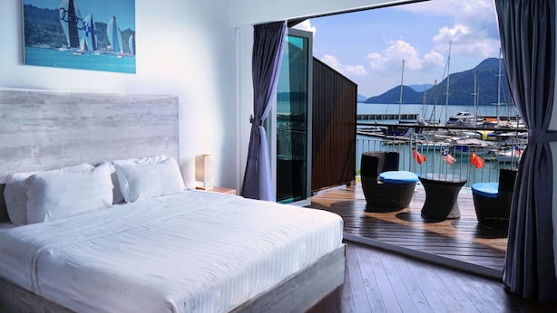 Ein Schlafzimmer mit einem großen Bett, Blick auf eine Marina mit Booten und einem Bild an der Wand.