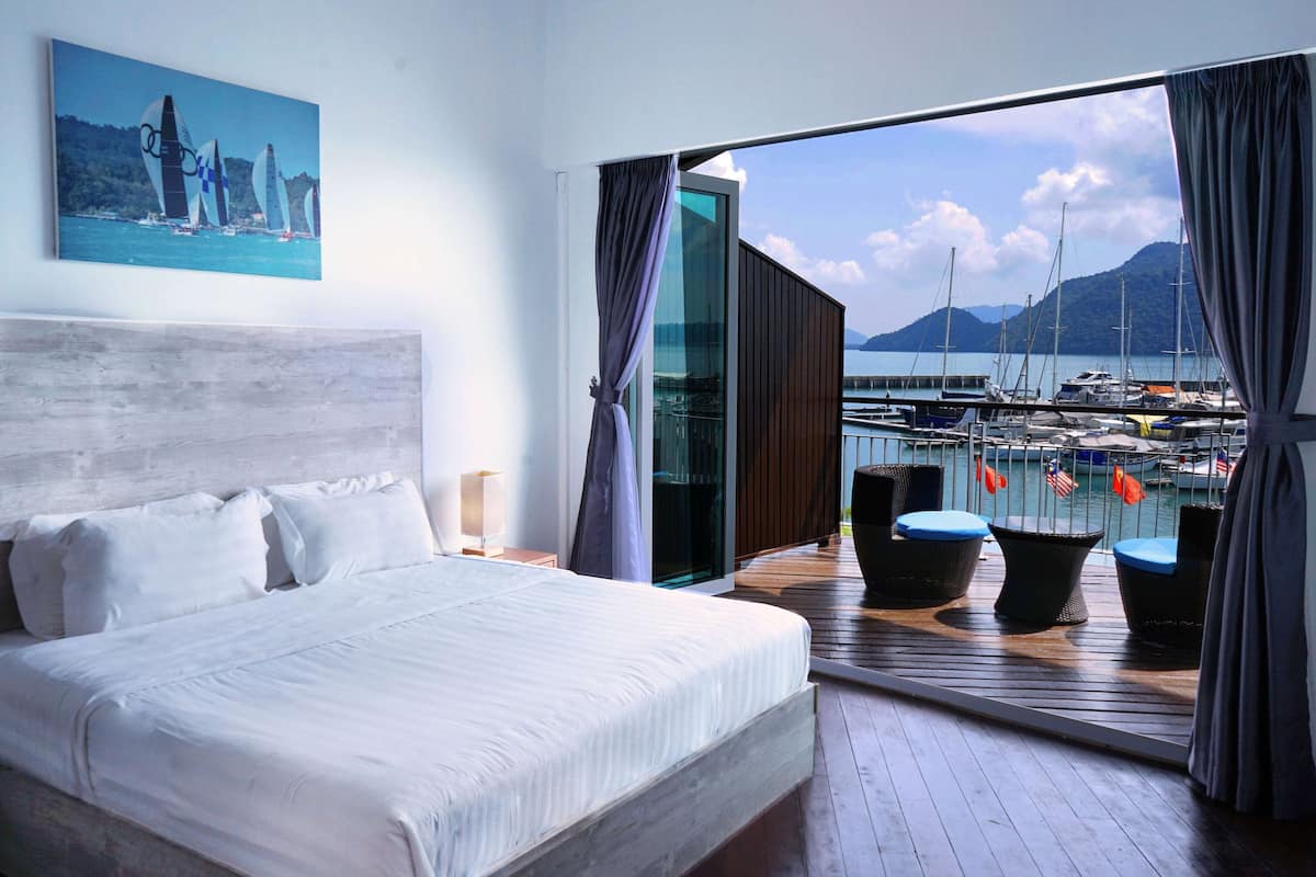 Une chambre avec un grand lit, une vue sur une marina remplie de bateaux et un tableau accroché au mur.