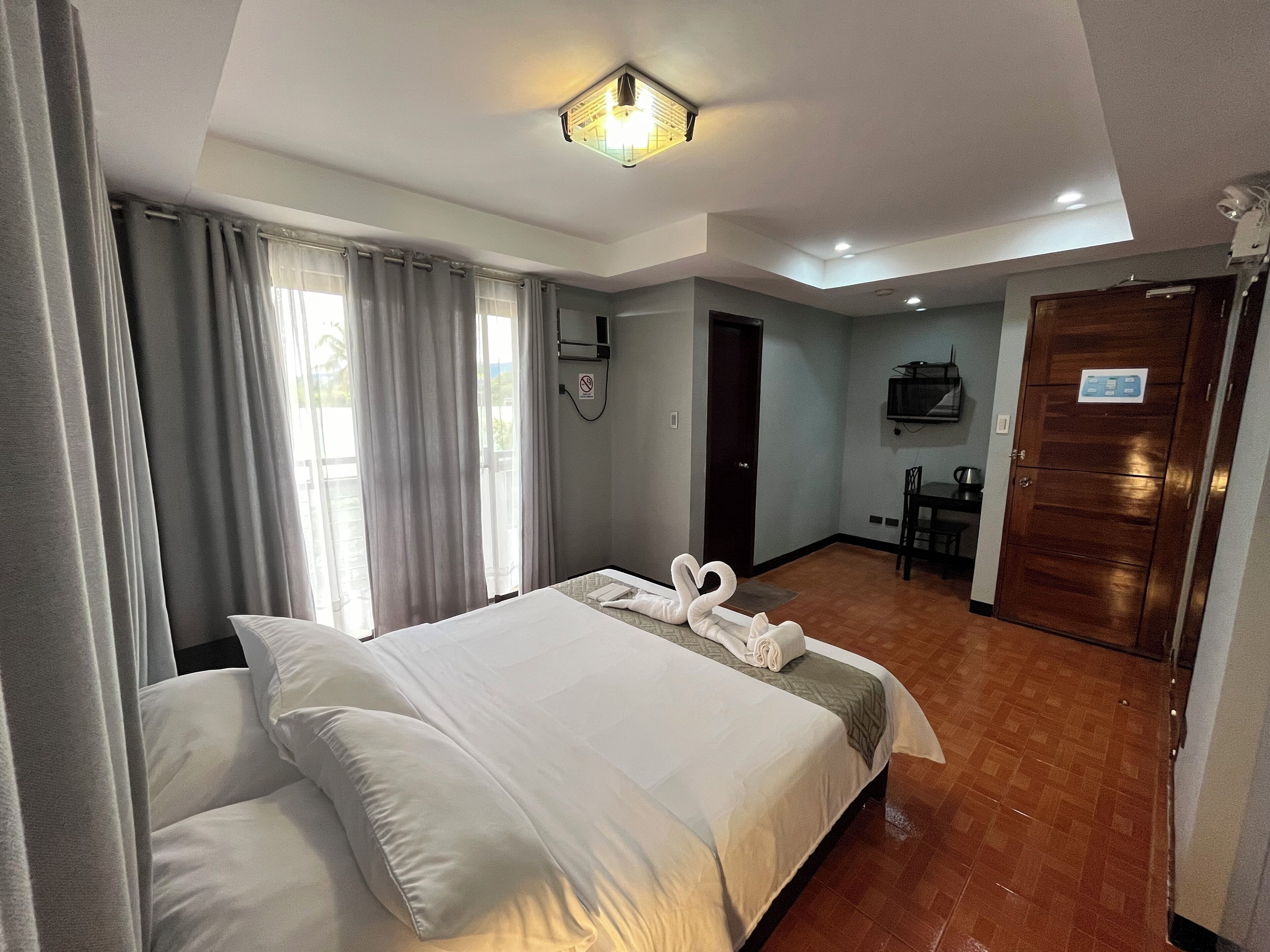 Une chambre d’hôtel avec un lit, un bureau, une chaise et une porte.