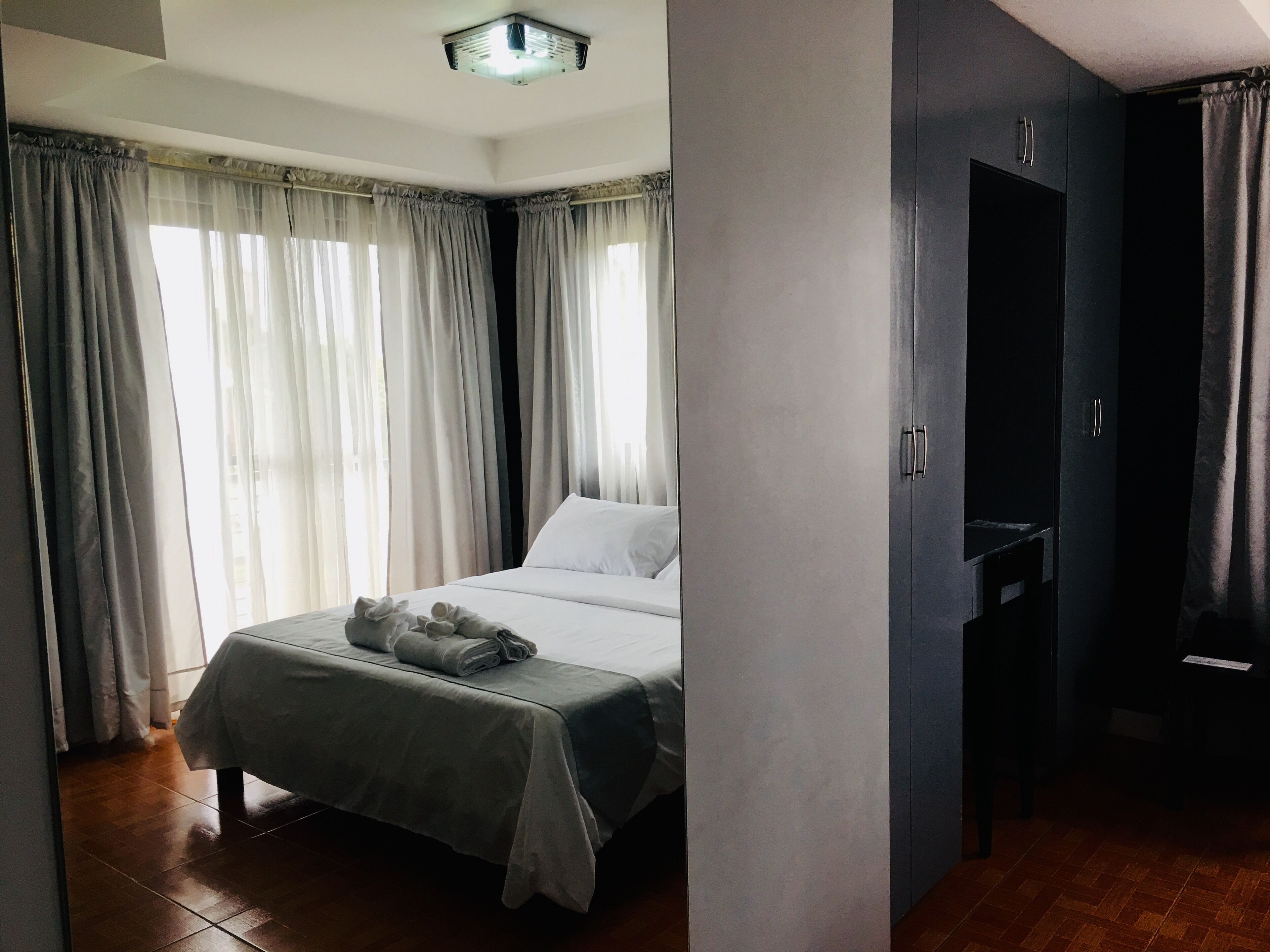 Ein Schlafzimmer mit Bett, Vorhängen, Kleiderschrank und Deckenleuchte.