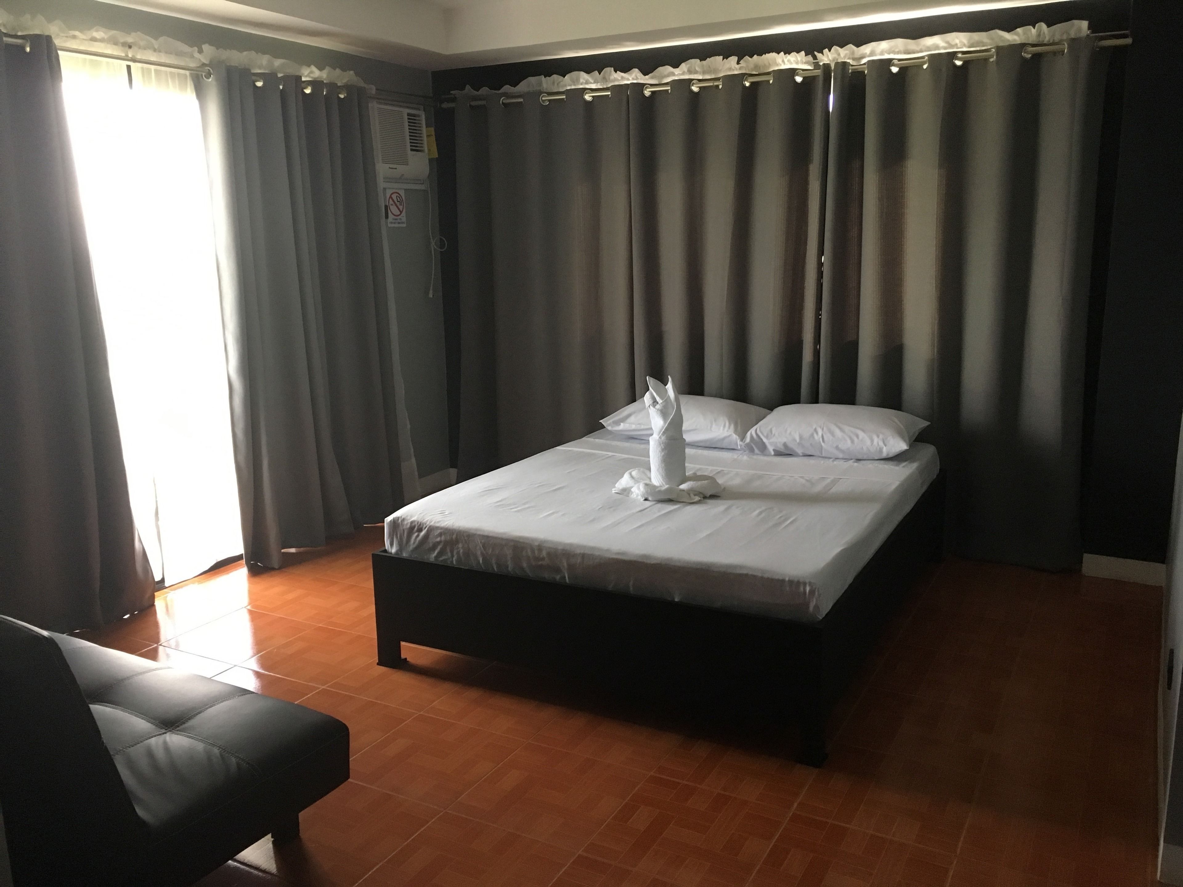 A hotel room with a bed, a chair, and curtains.