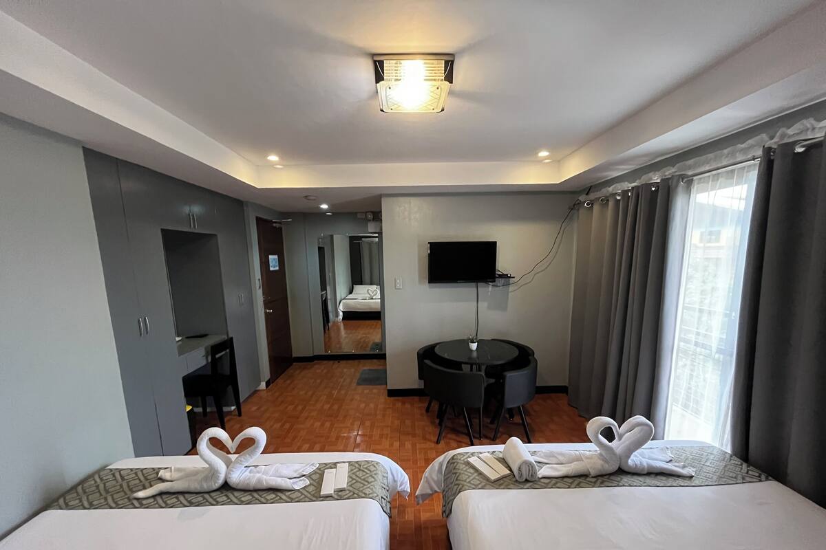 Une chambre d’hôtel avec deux lits, un bureau, une télévision et un miroir.