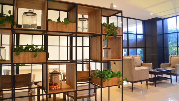 A modern living room with a wooden grid partition, comfortable seating, and potted plants.