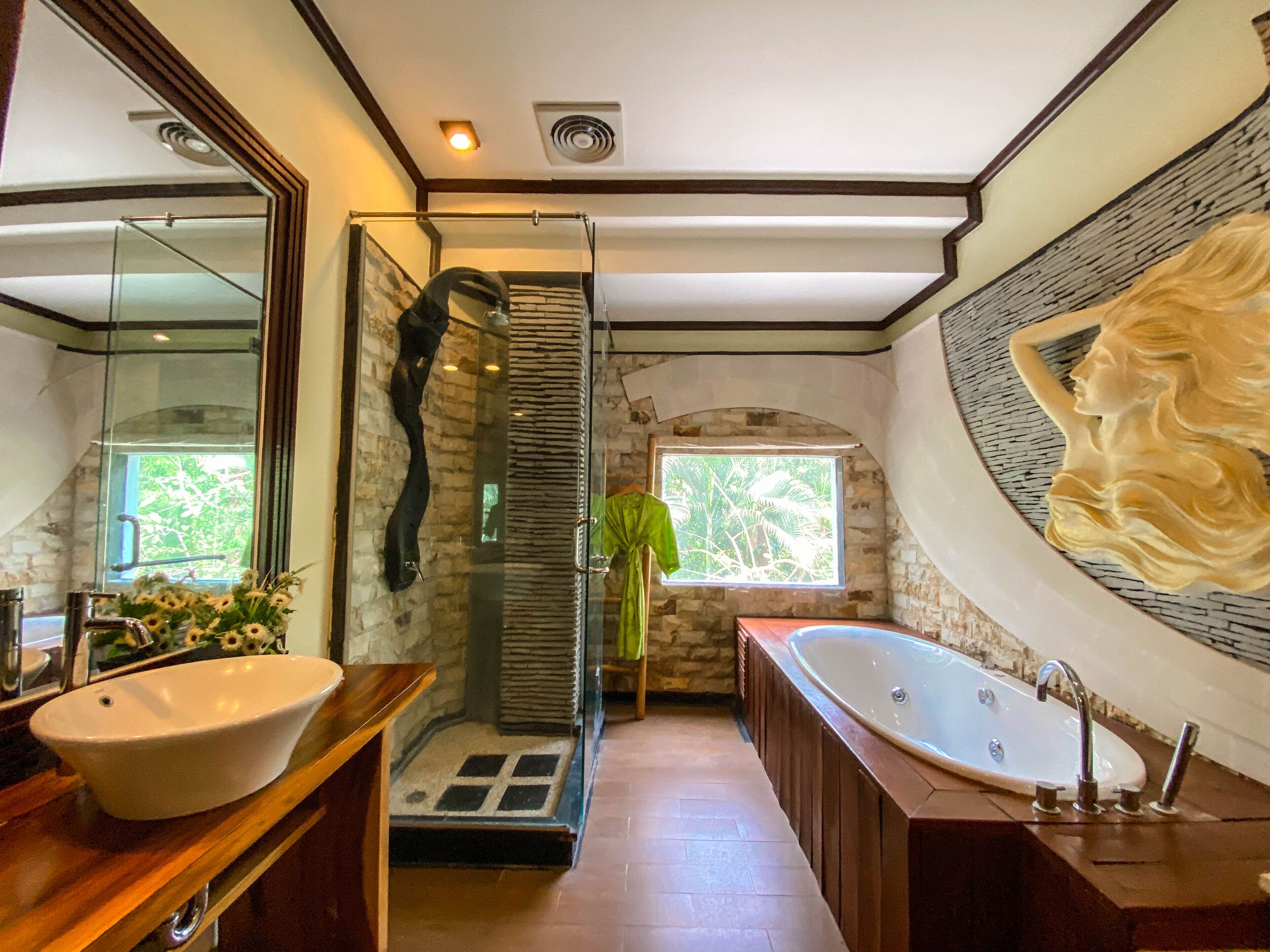 A modern bathroom with a large bathtub, a glass shower enclosure, and a large mirror.
