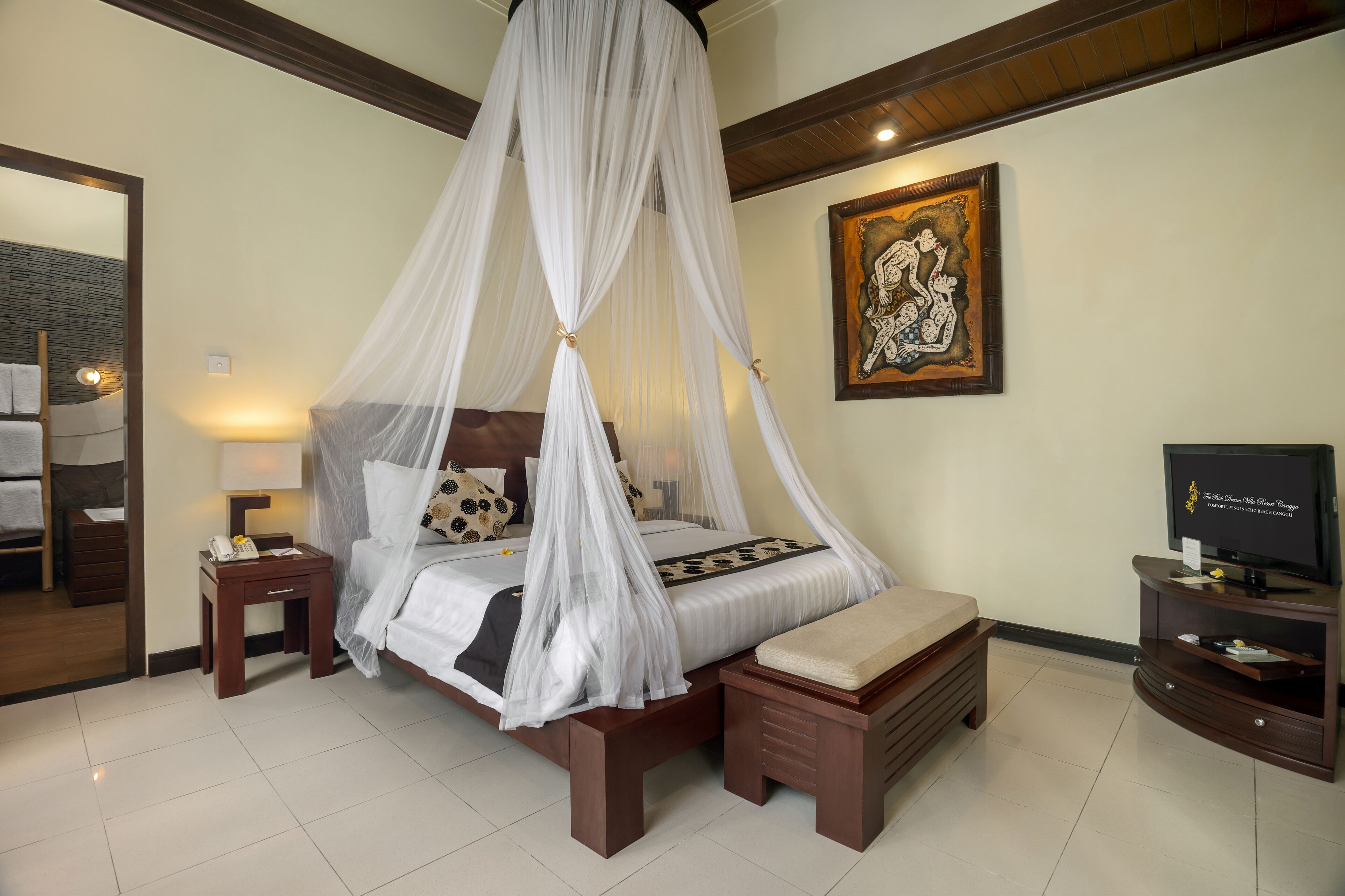 A bedroom with a four-poster bed, bedside tables, a television, and artwork on the wall.