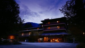 A traditional multi-story building with a large entrance and a mountain in the background. - Sekizenkan (Nakanojo)