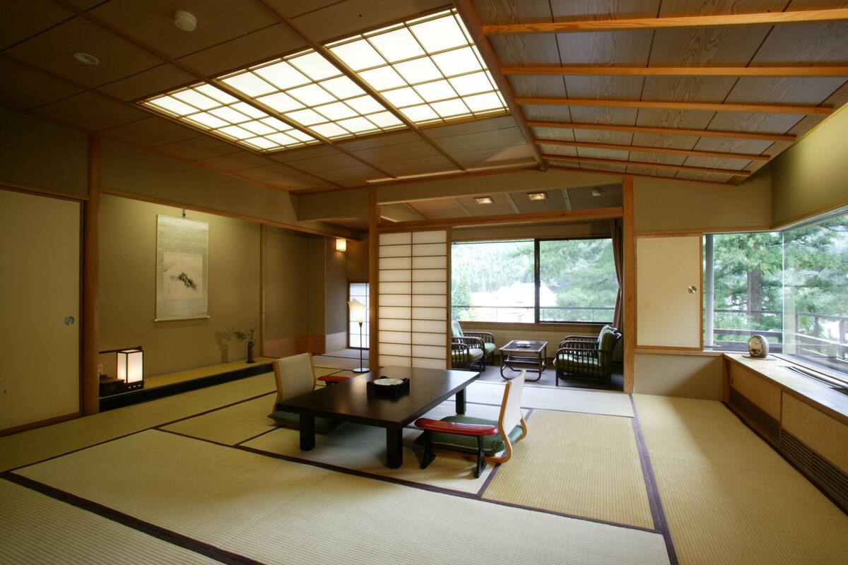 Una habitación japonesa tradicional con suelo de tatami, una mesa baja y puertas correderas.
