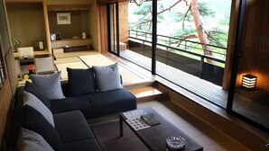 A traditional Japanese-style living room with tatami flooring, a low wooden table, and a sofa with cushions. - Sekizenkan (Nakanojo)