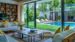 Una sala de estar moderna con un ventanal grande, piscina y estantería.
