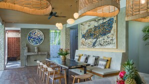 Una cocina moderna con una isla central, sillas de madera y una zona de estar con cojines.