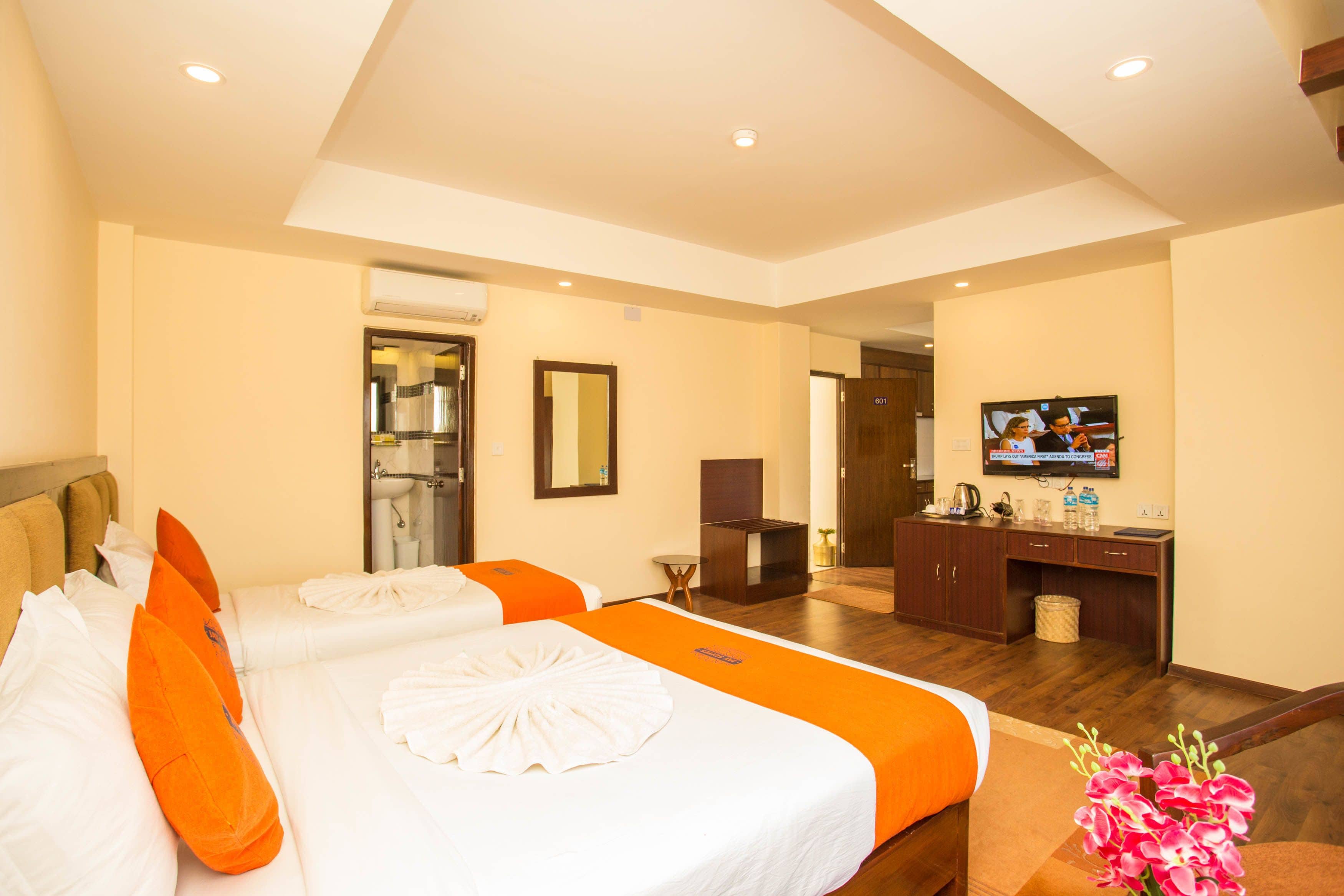 A hotel room with two beds, a TV, a desk, and a bathroom.
