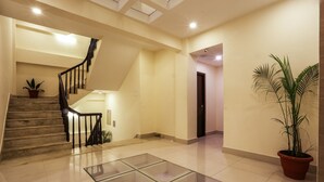 A spacious indoor area with a marble staircase, a glass coffee table, and potted plants. - Hotel Jay Suites (Kathmandu)