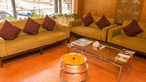 A hotel lobby with two sofas, a glass coffee table, and a copper pot with yellow food. - Hotel Jay Suites (Kathmandu)