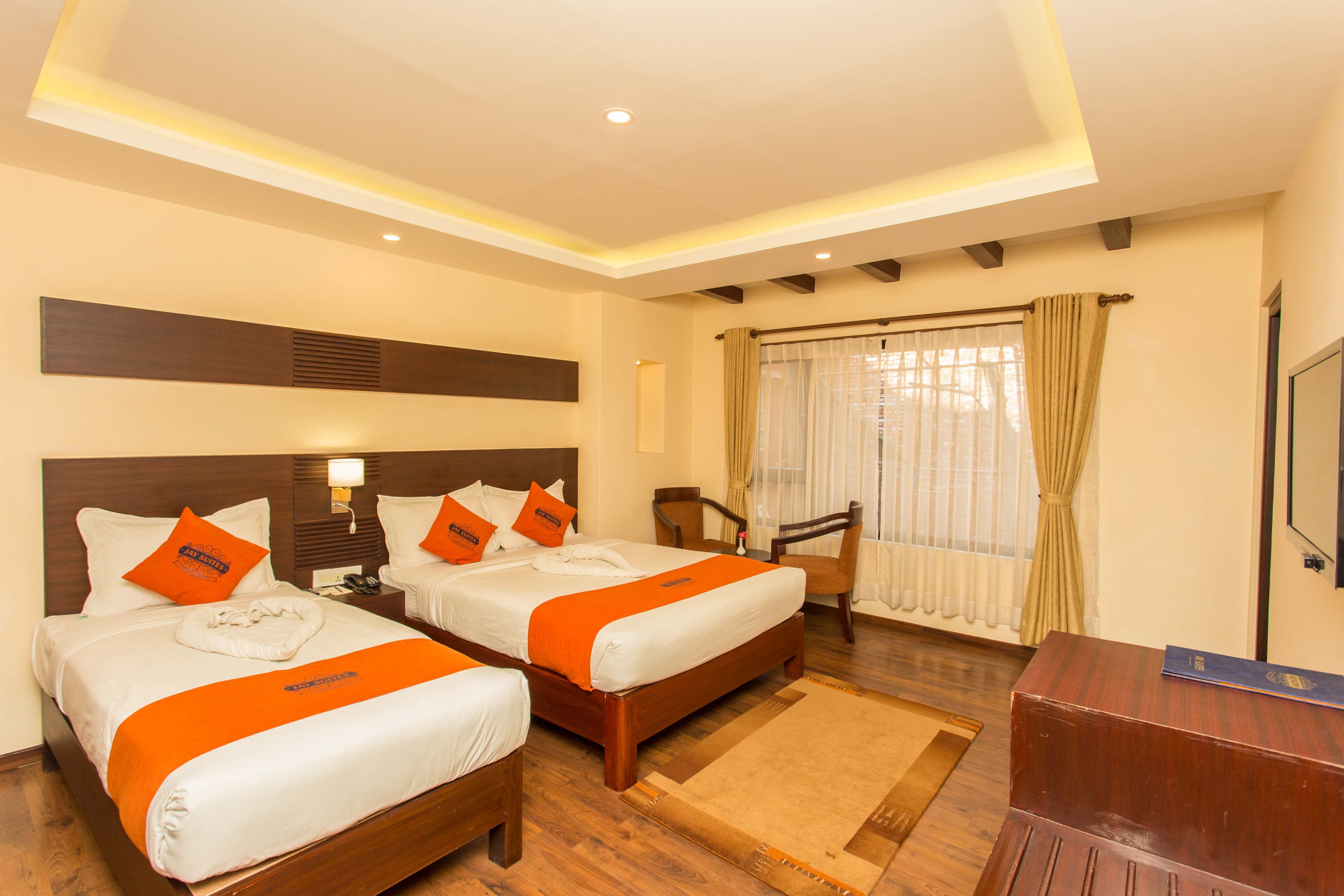 A hotel room with two beds, a desk, and a chair.