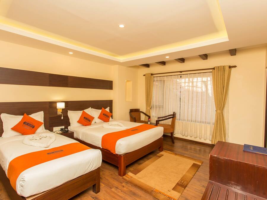 A hotel room with two beds, a desk, and a chair.
