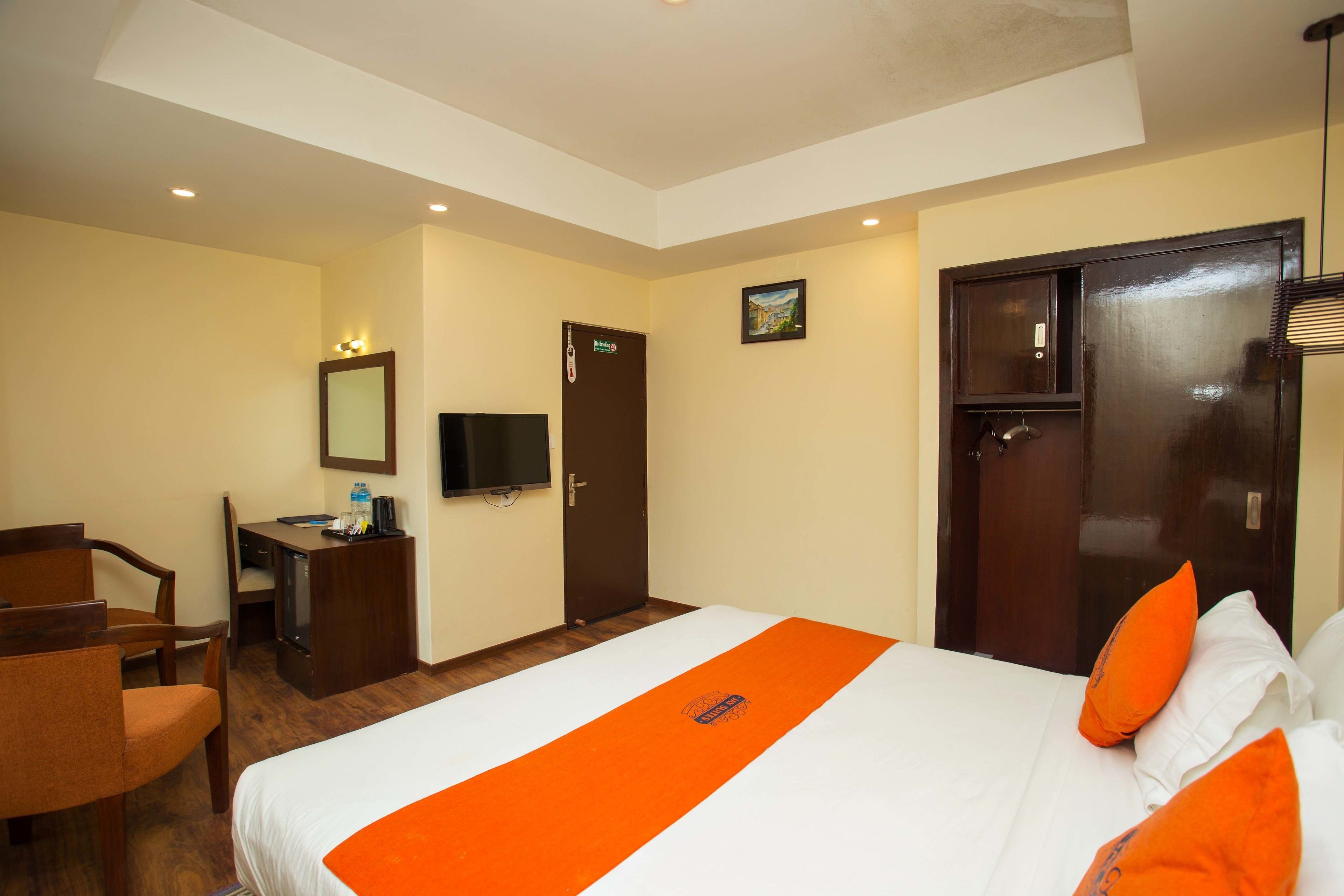 A hotel room with a bed, a desk, a chair, a television, and a door.
