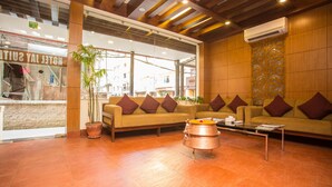 A lobby with two sofas, a coffee table, and a large window with a view of the street. - Hotel Jay Suites (Kathmandu)