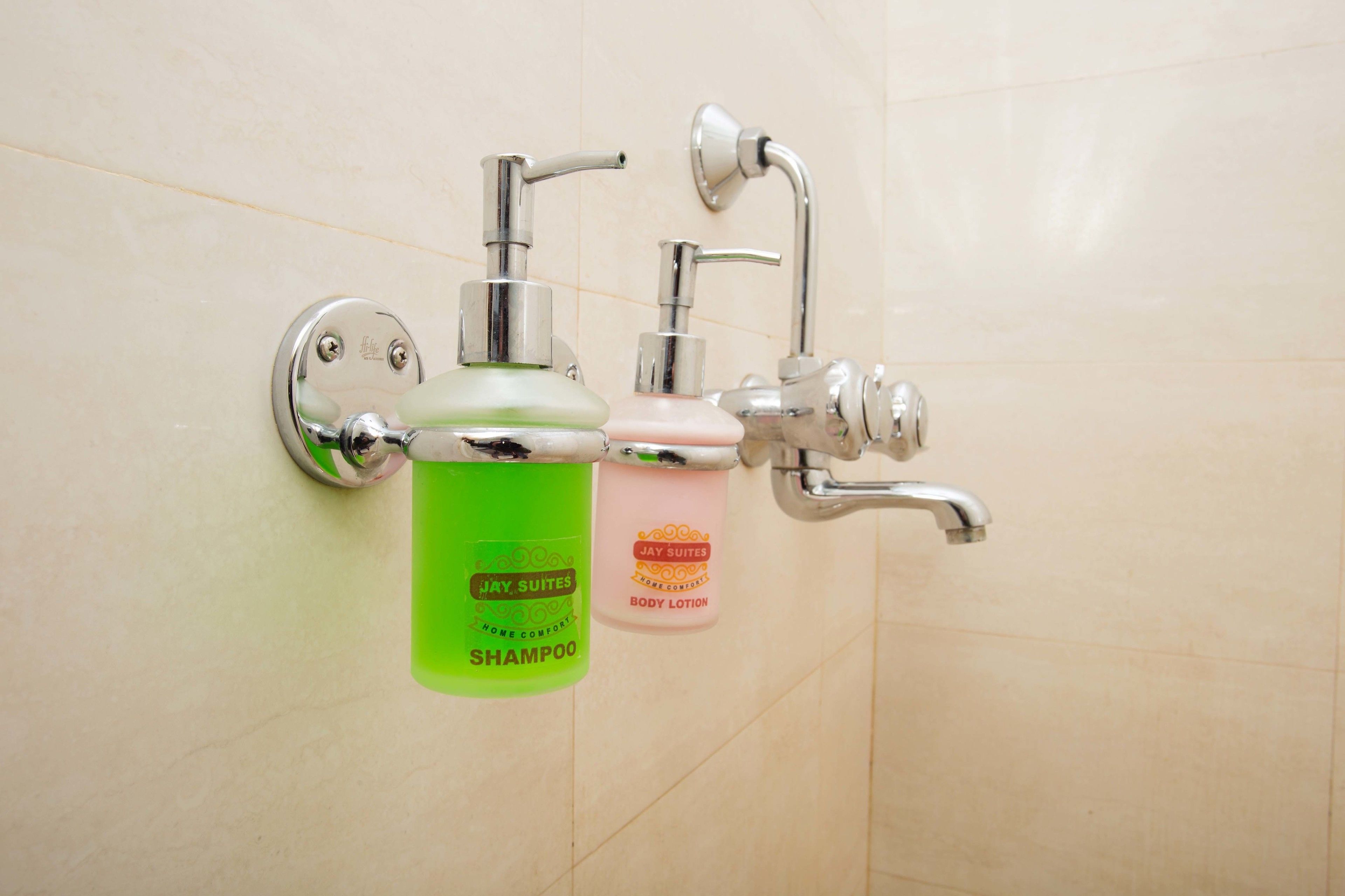 Ein Badezimmer mit einem wandmontierten Waschbecken, einem Wasserhahn und zwei Flaschen Shampoo und Körperlotion.