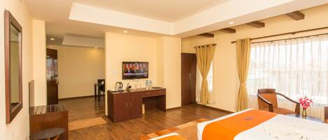 Habitación de hotel con dos camas, un escritorio, un televisor y un baño a la vista.