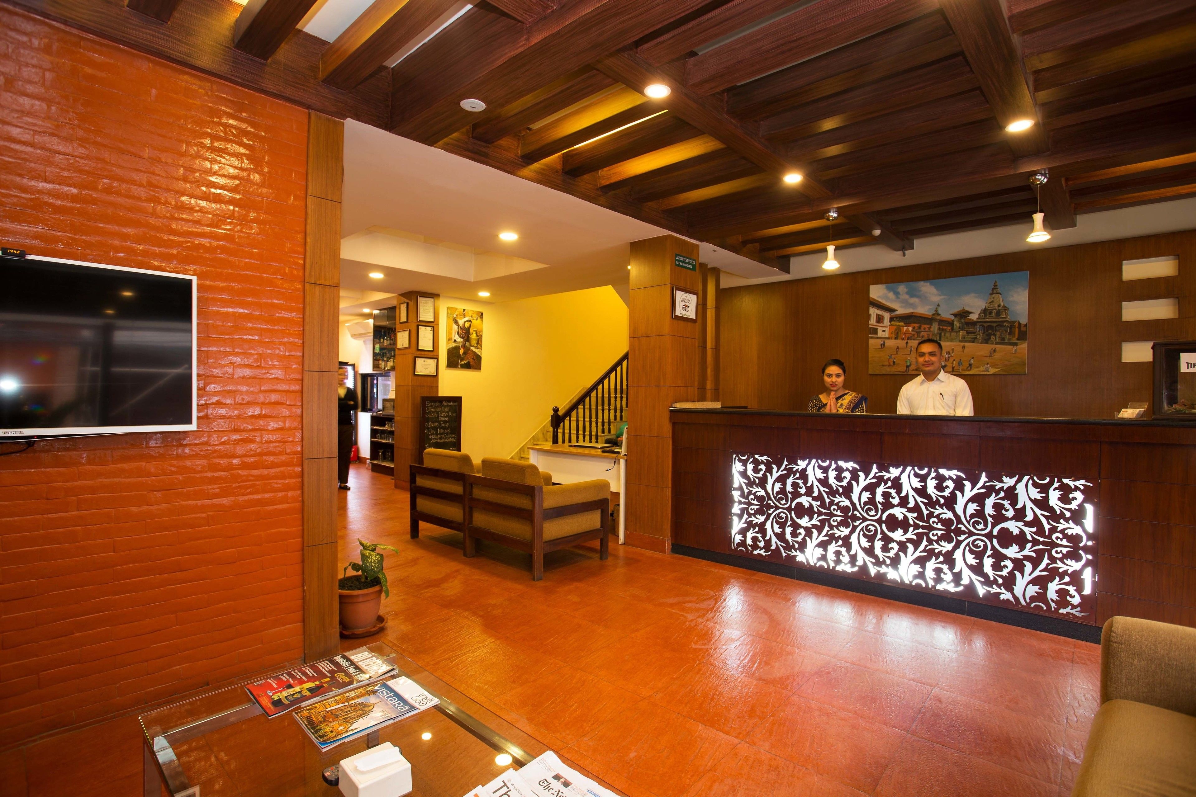 A hotel lobby with a reception desk, seating area, and a staircase leading to upper floors.