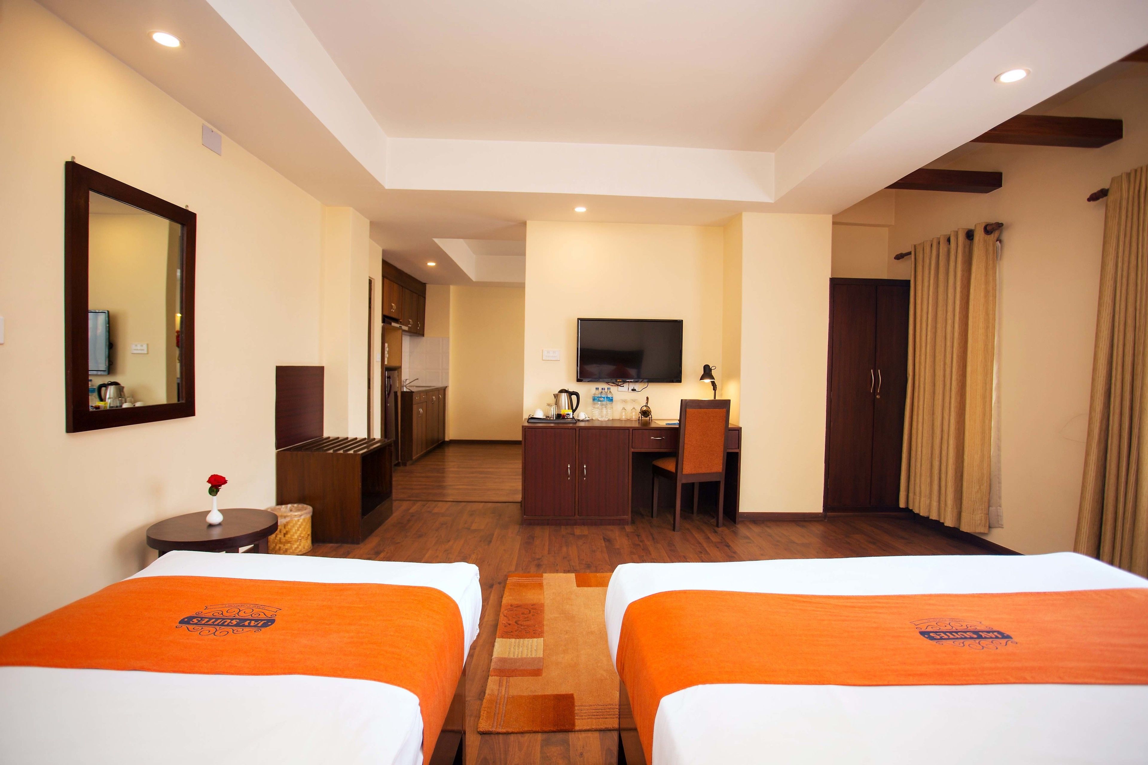 A hotel room with two beds, a desk, a television, and a mirror.