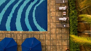 A swimming pool with tiled patterns, lounge chairs, and umbrellas. - Puri KIIC Golf View Hotel (Karawang)
