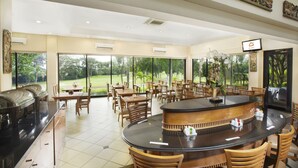 A restaurant with a central bar, multiple dining tables, and chairs. - Puri KIIC Golf View Hotel (Karawang)