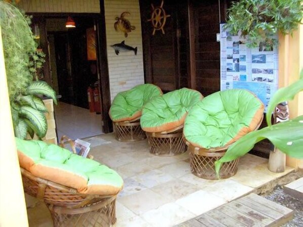 Wicker chairs with green cushions, a wooden floor, and a wall with a fish decoration.
