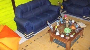 A room with two blue sofas, a wooden coffee table with various items, and a green wall with a painting. - Noronha Sol e Mar Pousada (Fernando de Noronha)