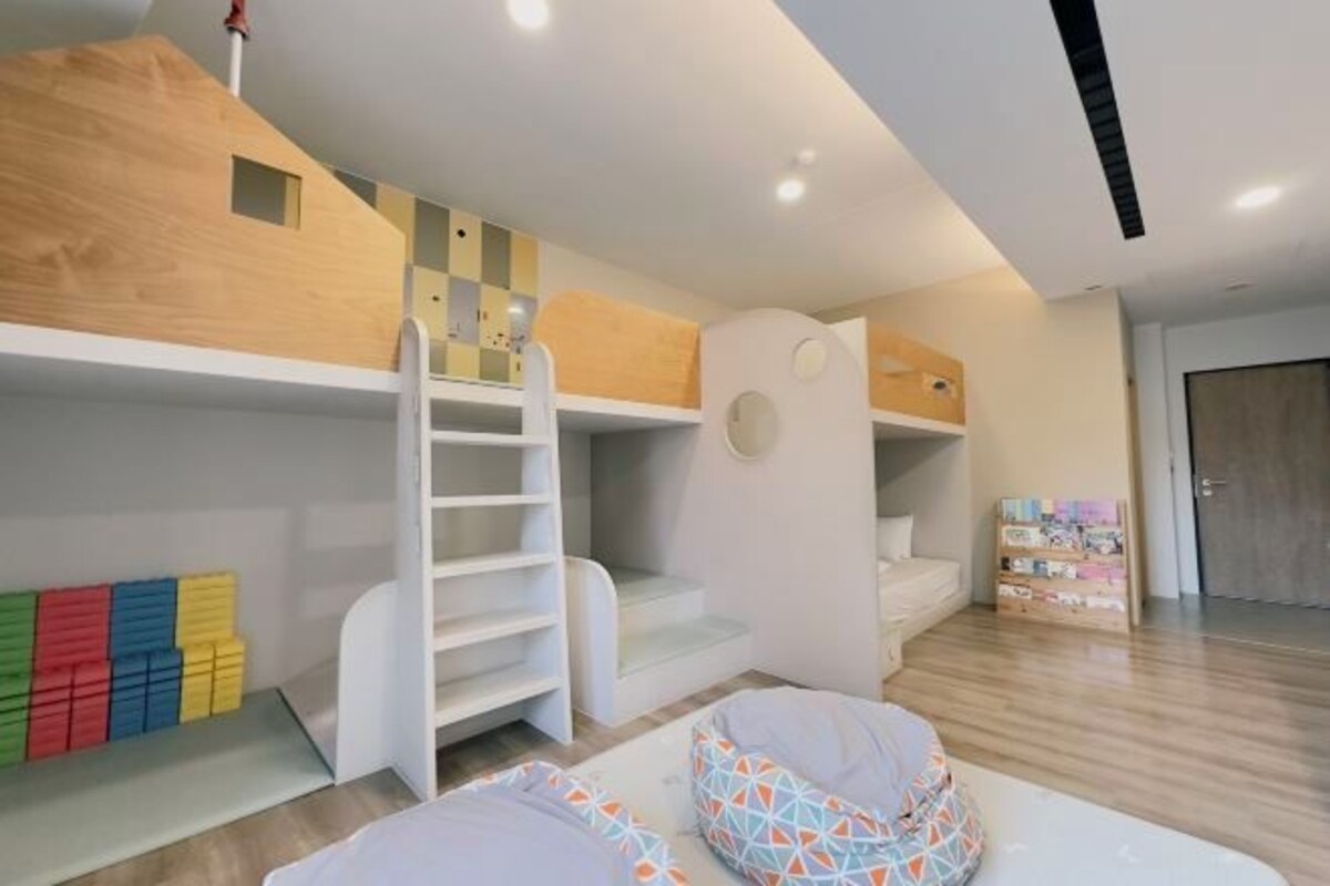 Una sala de juegos infantil con literas, una escalera y estanterías.