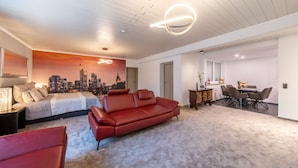 A modern bedroom with a cityscape mural, a red leather sofa, a dining area with a table and chairs, and a minimalist design. - PMC Business Apartments (Ruesselsheim)