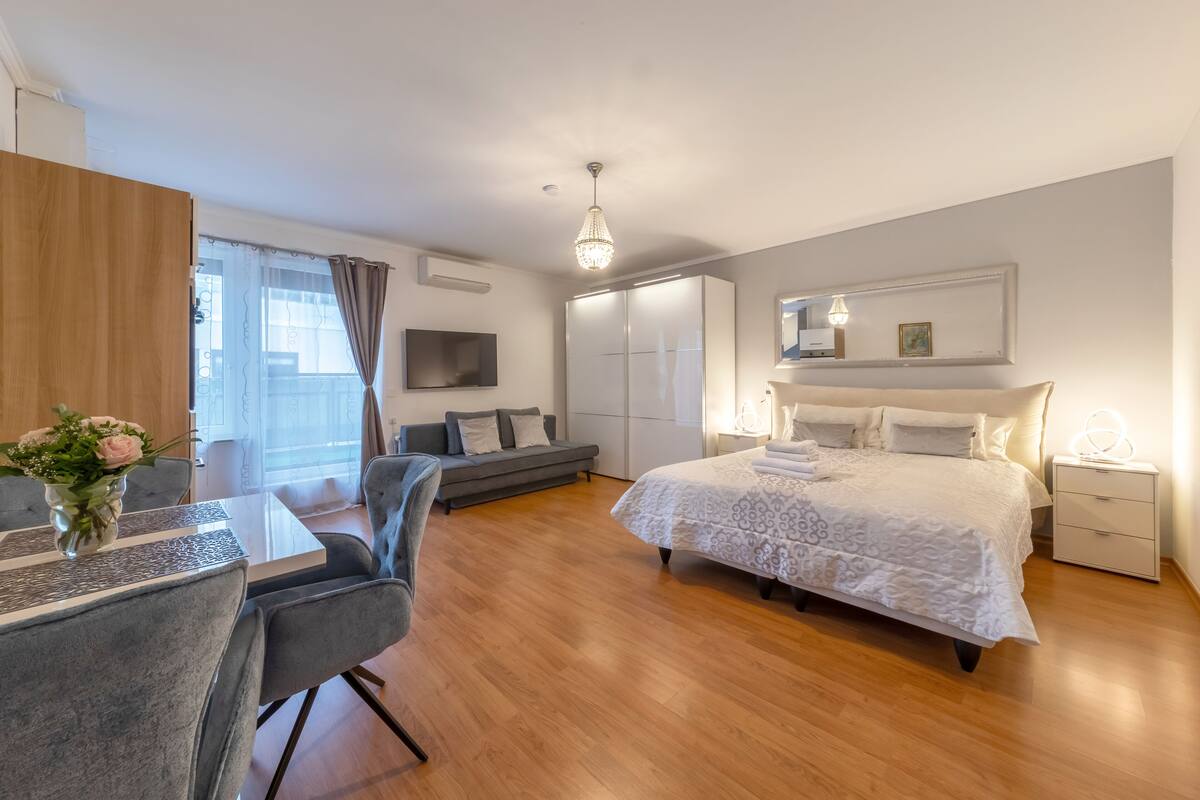 Quarto moderno com cama, mesas de cabeceira, escrivaninha e sofá.
