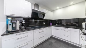 A modern kitchen with white cabinets, a black countertop, and a built-in stove. - PMC Business Apartments (Ruesselsheim)