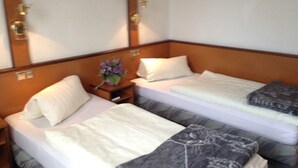 Ein Hotelzimmer mit zwei Betten, einem Nachttisch mit Blumenvase und einem Spiegel über den Betten.