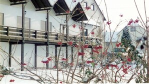Ein weißes Gebäude mit mehreren schrägen Dächern und einem Balkon.