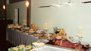 Ein reichhaltiges Buffet mit verschiedenen Speisen, darunter ein großes Spanferkel, Früchte und Salate.